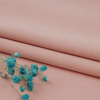 A sprig of small blue dried flowers rests on neatly folded, soft pink Multiple Colors Linen Fabric By The Yard—washed cotton linen blend clothing material by Longan Craft.