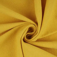 A close-up of yellow Multiple Colors Linen Fabric By The Yard from Longan Craft, a washed cotton linen blend for apparel, twisted into a spiral to display its texture and soft folds.