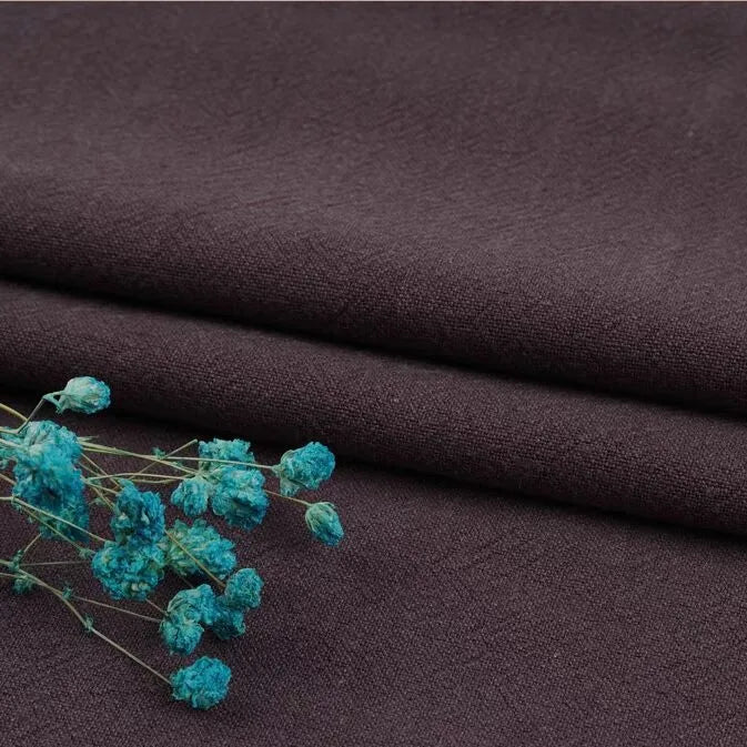 A close-up of two neatly folded pieces of Longan Craft's Multiple Colors Linen Fabric By The Yard with bright turquoise dried flowers, showcasing the durable washed cotton linen blend ideal for apparel.