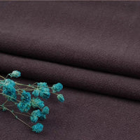 A close-up of two neatly folded pieces of Longan Craft's Multiple Colors Linen Fabric By The Yard with bright turquoise dried flowers, showcasing the durable washed cotton linen blend ideal for apparel.