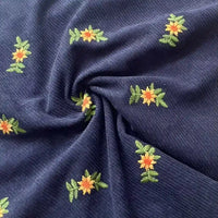 Longan Craft’s Thick 8 Wale Polyester Corduroy Fabric By The Yard features navy blue corduroy with yellow and orange floral embroidery—ideal for unique, elegant upholstery or fall apparel.