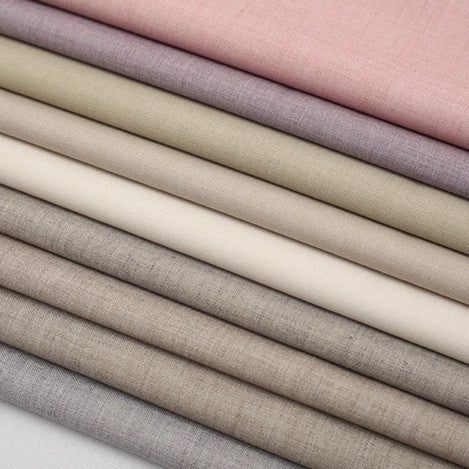 Stacked folds of Colorful Worsted Wool Fabric By The Yard in multicolor shades of pink, lavender, beige, and grey.
