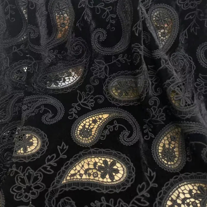 Paisley Embroidered Velvet Fabric By The Yard from Longon Craft features hollow-out floral and paisley embroidery on black velvet, perfect for DIY autumn and winter dresses or luxury gowns.