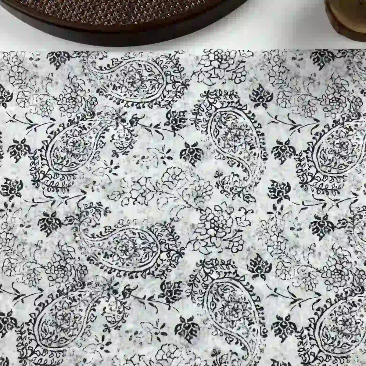 Longan Craft Paisley Printed Voile Fabric by the yard features pure cotton with black and white paisley and floral patterns, ideal for shirts. A brown textured object and a round item appear in the top corners.
