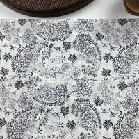 Longan Craft Paisley Printed Voile Fabric by the yard features pure cotton with black and white paisley and floral patterns, ideal for shirts. A brown textured object and a round item appear in the top corners.