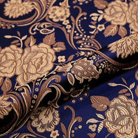 A close-up of Longan Craft's Peony Jacquard Brocade Fabric by the Yard, a colorful Chinese floral brocade featuring gold peonies and leaves on dark blue, slightly folded to showcase its detailed design—ideal for formal dresses and elegant bridal gowns.