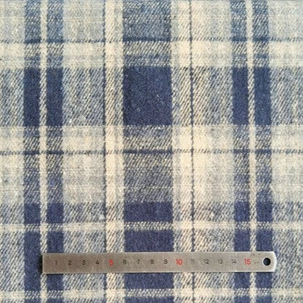 A Longan Craft metal ruler measures about 16 cm on Plaid Brushed Mammoth Flannel Fabric By The Yard, a comfy polyester cotton material with intersecting blue and off-white lines—perfect for cozy fall projects.