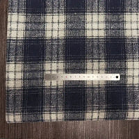 A metal ruler rests on a Longan Craft Plaid Brushed Mammoth Flannel Fabric by the yard, featuring colorful polyester-cotton flannel, with the fabric laid on a wooden surface.