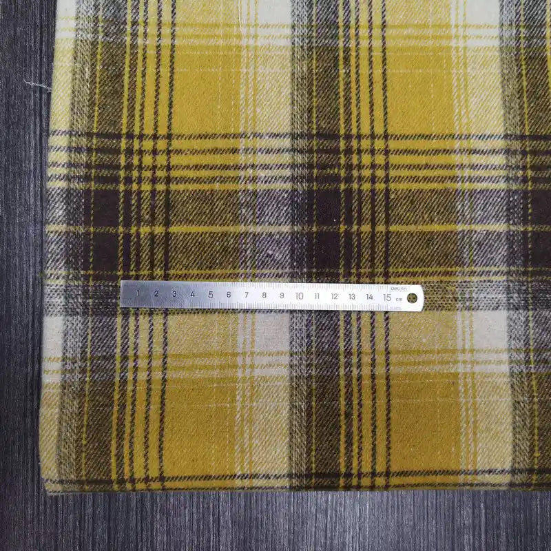 A metal ruler lies across Longan Craft’s Plaid Brushed Mammoth Flannel Fabric by the yard, a colorful polyester-cotton flannel with a bold check pattern and soft texture—ideal for comfy fall projects.