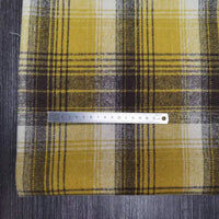 A metal ruler lies across Longan Craft’s Plaid Brushed Mammoth Flannel Fabric by the yard, a colorful polyester-cotton flannel with a bold check pattern and soft texture—ideal for comfy fall projects.