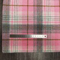 A Longan Craft Plaid Brushed Mammoth Flannel Fabric (polyester-cotton), shown in pink, white, gray, and brown plaid, is displayed on a dark wood surface with a 15 cm metal ruler measuring its width.