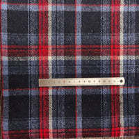 A metal ruler lays atop Longan Craft’s Plaid Brushed Mammoth Flannel Fabric, showcasing its colorful checked pattern. This comfy polyester-cotton flannel is sold by the yard and perfect for fall projects.