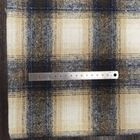 A metal ruler measuring 16 cm rests horizontally on Longan Craft's Plaid Brushed Mammoth Flannel Fabric, a colorful polyester cotton flannel with beige, navy blue, and brown checks, showing the scale of the pattern.