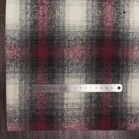A metal ruler measuring about 15cm lies on Longan Craft's Plaid Brushed Mammoth Flannel Fabric—a colorful polyester-cotton material in black, red, and white—displayed on a wooden surface.