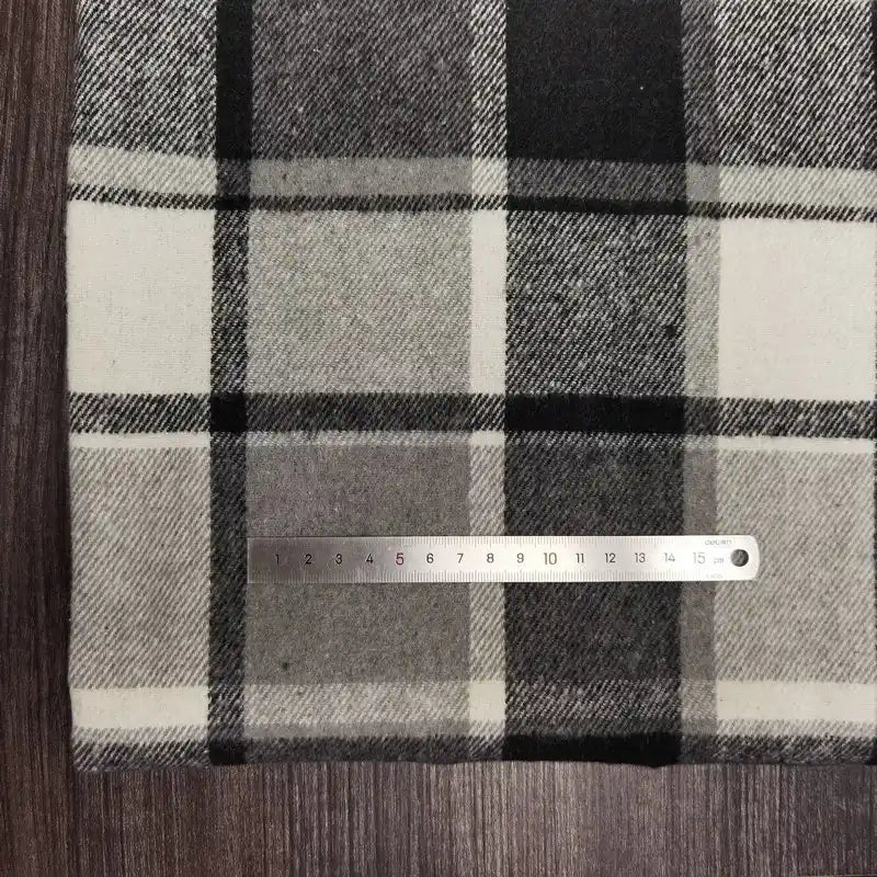 A metal 15cm ruler lies on Longan Craft Plaid Brushed Mammoth Flannel Fabric—a comfy, colorful polyester-cotton flannel—spread across a wooden surface.