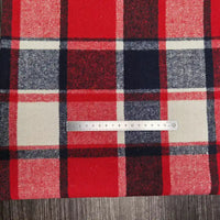 A Longan Craft Plaid Brushed Mammoth Flannel Fabric in red, navy, white, and black is shown on a dark wood surface with a metal ruler measuring one square; this cozy polyester cotton flannel is sold by the yard.