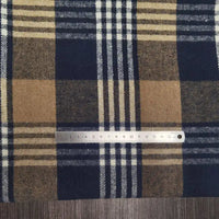 A metal ruler measures up to 15 centimeters on Longan Craft’s Plaid Brushed Mammoth Flannel Fabric by the Yard, a comfy polyester cotton material featuring a blue, tan, and cream checkered pattern.