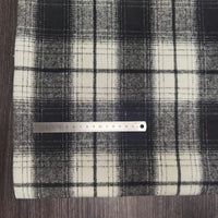 A metal ruler measuring about 18 cm lies horizontally on Longan Craft Plaid Brushed Mammoth Flannel Fabric, a colorful polyester-cotton material, displayed on a wood-textured surface.