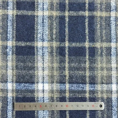 A close-up of Longan Craft Plaid Brushed Mammoth Flannel Fabric by the yard, featuring blue, white, and beige lines next to a metal ruler (0-15 cm). This colorful polyester cotton flannel is perfect for comfy fall projects.