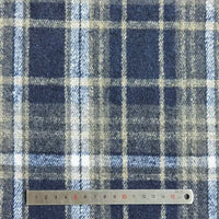 A close-up of Longan Craft Plaid Brushed Mammoth Flannel Fabric by the yard, featuring blue, white, and beige lines next to a metal ruler (0-15 cm). This colorful polyester cotton flannel is perfect for comfy fall projects.