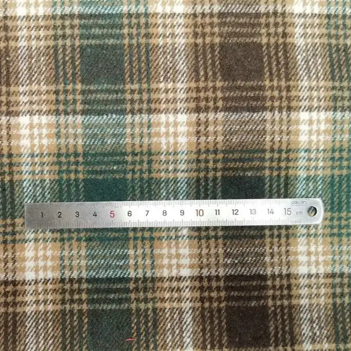 A 15 cm metal ruler rests on Longan Craft's Plaid Brushed Mammoth Flannel Fabric, a colorful polyester-cotton material with a green, brown, beige, and white checkered pattern—perfect for comfy fall creations.