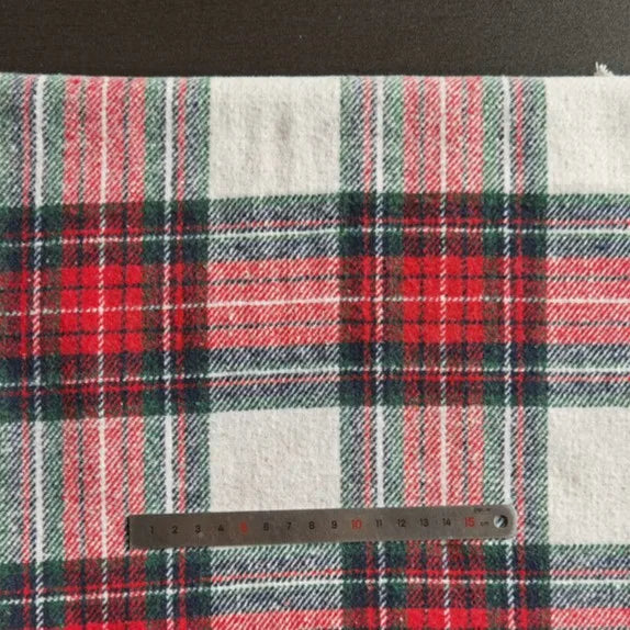 The Longan Craft Plaid Brushed Mammoth Flannel Fabric By The Yard, a colorful polyester cotton fall flannel, is shown on a flat surface with a metal centimeter ruler at the bottom for size reference.