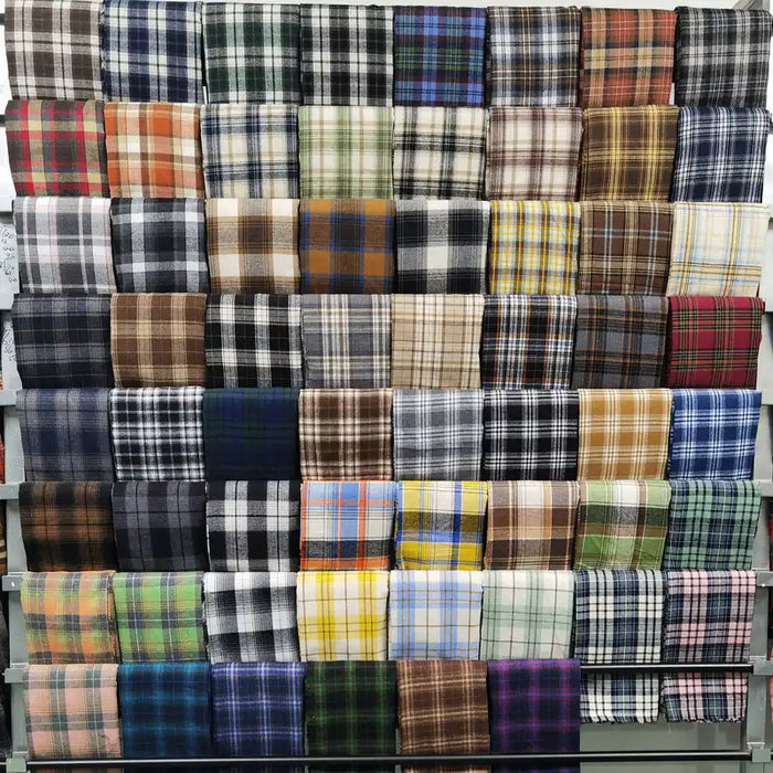 Longan Craft's Plaid Brushed Mammoth Flannel Fabric by the yard features colorful polyester-cotton blends in cozy checkered designs, neatly stacked to showcase a wide variety of comfy fall flannels.