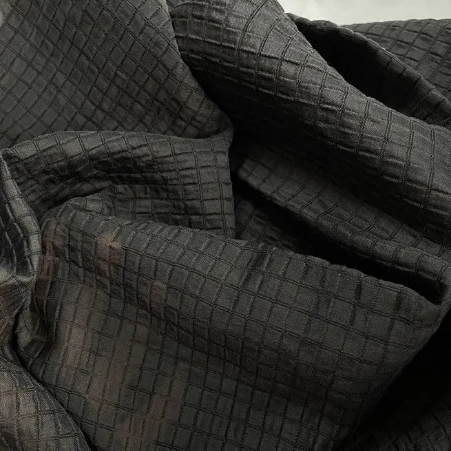 A close-up of Longan Craft’s Plaid Jacquard Lyocell Fabric by the Yard reveals its multicolor checked, breathable textile with a subtle raised pattern and gently wrinkled texture—ideal for sustainable apparel projects.