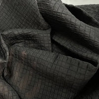 A close-up of Longan Craft’s Plaid Jacquard Lyocell Fabric by the Yard reveals its multicolor checked, breathable textile with a subtle raised pattern and gently wrinkled texture—ideal for sustainable apparel projects.