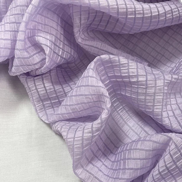 A close-up of Longan Craft Plaid Jacquard Lyocell Fabric By The Yard, featuring a breathable multicolor checked pattern and crinkled texture, smoothly draped over a light surface—ideal for apparel.