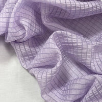 A close-up of Longan Craft Plaid Jacquard Lyocell Fabric By The Yard, featuring a breathable multicolor checked pattern and crinkled texture, smoothly draped over a light surface—ideal for apparel.