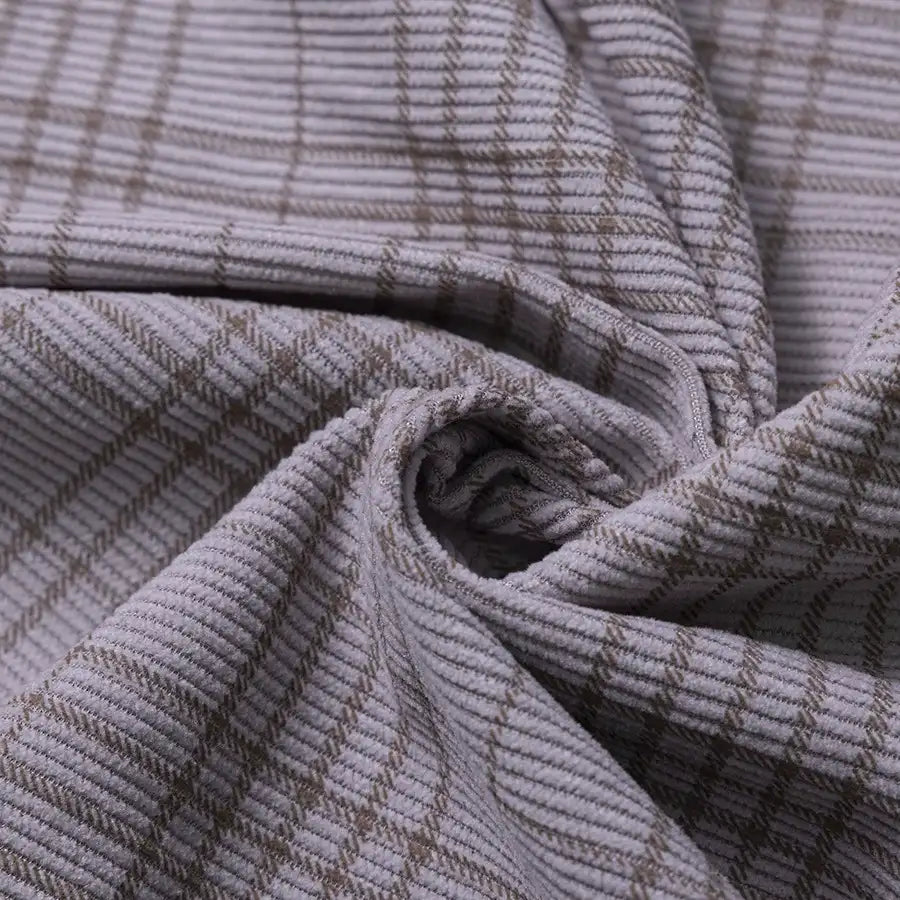 Close-up of the Longan Craft Plaid Print 16 Wale Corduroy Fabric By The Yard, featuring a light gray grid pattern and fine, textured ridges. The colorful, premium corduroy material is shown twisted at the center to showcase its flexibility and detailed surface—making it an ideal choice for pants or any versatile sewing project.