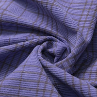 Close-up of the Longan Craft Plaid Print 16 Wale Corduroy Fabric By The Yard, featuring a colorful purple design with fine gray plaid lines, gathered and twisted at the center. This premium fine wale corduroy material is ideal for sewing stylish and textured projects like pants.