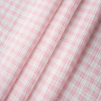 Close-up of Plaid Print Double Gauze Fabric By The Yard from Longan Craft, featuring a pink and white gingham checkered pattern in pure cotton. This cozy gauze material displays soft folds and a textured surface, making it a breathable and comfortable choice for baby clothing and stylish sewing projects.