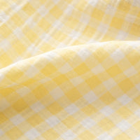 Close-up of the Plaid Print Double Gauze Fabric By The Yard from Longan Craft, featuring a yellow and white checked pattern on pure cotton gauze material. The soft folds and airy texture highlight the fabric’s breathable qualities, making it ideal for cozy baby clothing.