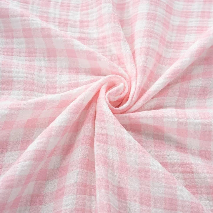 Longan Craft’s Plaid Print Double Gauze Fabric By The Yard, crafted from pure cotton and featuring a pink and white checkered pattern, is arranged in a gentle swirl at the center to showcase its soft, cozy texture and light, airy appearance—an ideal choice for those seeking breathable material with timeless charm for baby clothing.