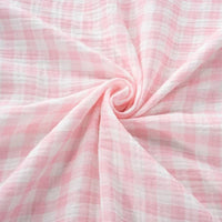 Longan Craft’s Plaid Print Double Gauze Fabric By The Yard, crafted from pure cotton and featuring a pink and white checkered pattern, is arranged in a gentle swirl at the center to showcase its soft, cozy texture and light, airy appearance—an ideal choice for those seeking breathable material with timeless charm for baby clothing.