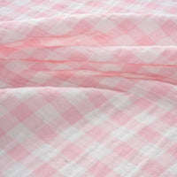 Close-up of Longan Craft’s Plaid Print Double Gauze Fabric by the yard, featuring a pink and white pure cotton checkered print with a soft, textured surface and gentle folds, highlighting its cozy and breathable qualities—perfect for baby clothing.