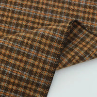 Plaid Wool Fabric By The Yard in brown, orange, and gray with a serged edge.