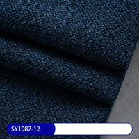 Close-up of Longan Craft Plain Color Boucle Fabric By The Yard, thick polyester material in dark blue, folded as upholstery fabric on a light grey surface. Bottom left label reads SY1087-12 in white text on blue.