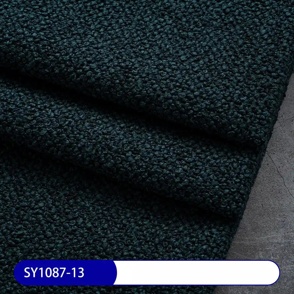 Close-up of Longan Craft Plain Color Boucle Fabric By The Yard, thick polyester upholstery material, neatly folded on a gray surface. Ideal for drapery or upholstery. Label at bottom left shows SY1087-13 in white on blue.