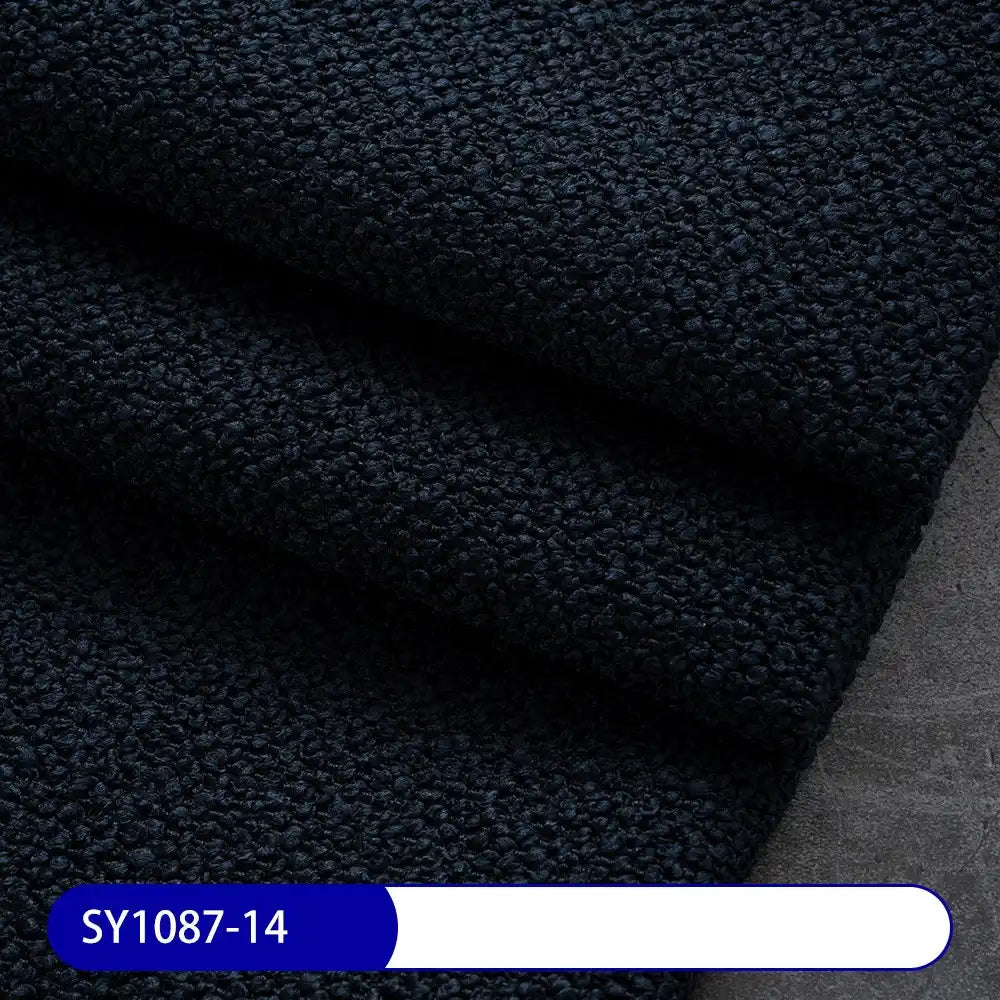 A close-up of folded, textured dark navy blue Plain Color Boucle Fabric By The Yard from Longan Craft on a gray surface, with label SY1087-14—thick polyester boucle perfect for upholstery or drapery fabric projects.