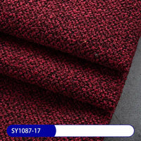 Close-up of thick, dark red Plain Color Boucle Fabric By The Yard from Longan Craft, folded in layers on a gray surface. A blue and white label at the bottom left corner reads “SY1087-17.”.