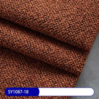 Close-up of brown Plain Color Boucle Fabric By The Yard from Longan Craft, showcasing its thick, textured upholstery pattern and folded layers. The sample code SY1087-18 is displayed in white on a blue label at the bottom.