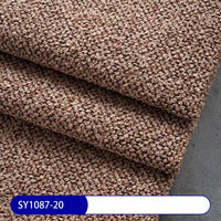 Close-up of textured, brown Plain Color Boucle Fabric By The Yard from Longan Craft neatly folded on a gray surface. A blue and white label shows code SY1087-20—perfect thick polyester boucle upholstery fabric for projects.
