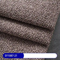 Close-up of folded brown Plain Color Boucle Fabric By The Yard by Longan Craft, featuring a thick looped, pebble-like surface; ideal for upholstery or drapery. A label at the bottom reads SY1087-21 on a white and blue background.