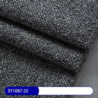 Close-up of thick, dark gray Plain Color Boucle Fabric By The Yard from Longan Craft, neatly folded in layers. A blue label at the bottom reads SY1087-25. Ideal for drapery or upholstery projects.