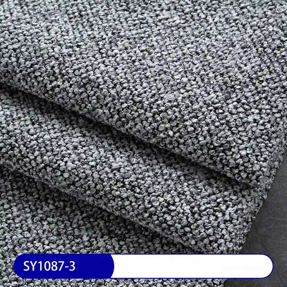 Close-up of Plain Color Boucle Fabric By The Yard from Longan Craft, thick polyester upholstery material in textured gray folds. The looped surface is ideal for upholstery. Label at bottom left: SY1087-3 on blue and white.