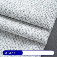 Close-up of Longan Craft’s Plain Color Boucle Fabric By The Yard, a thick polyester upholstery material in light gray with a pebble-like texture. The label at the bottom reads SY1087-7 in white on blue.