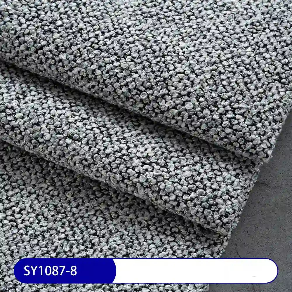 Close-up of three overlapping pieces of Longan Craft Plain Color Boucle Fabric By The Yard, thick polyester upholstery material in textured gray, with a label reading SY1087-8—ideal for versatile upholstery projects.